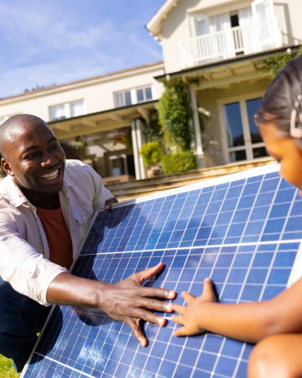 Outdoors, diverse father and daughter interacting with solar panel
